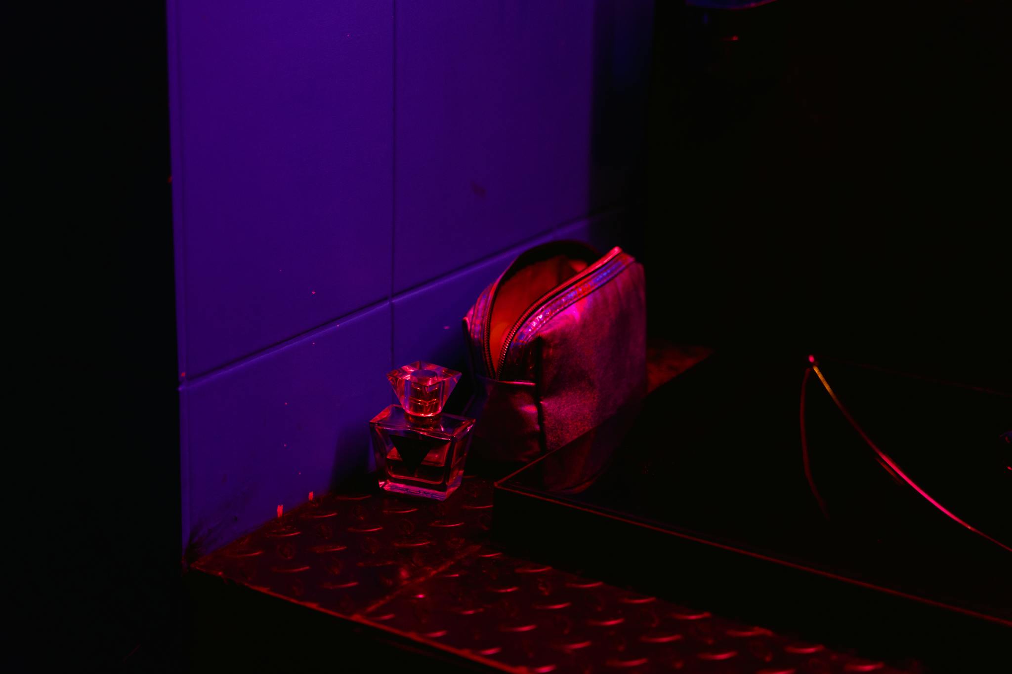 A shot glass and purse illuminated by vibrant nightclub lighting.